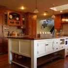 glazed cherry cabinet kitchen with matching paneled refrigerator and antique white island - crown point kitchen cabinets - via atticmag