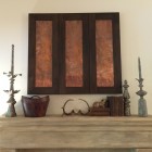 tv over the fireplace concealed behind sliding copper panels